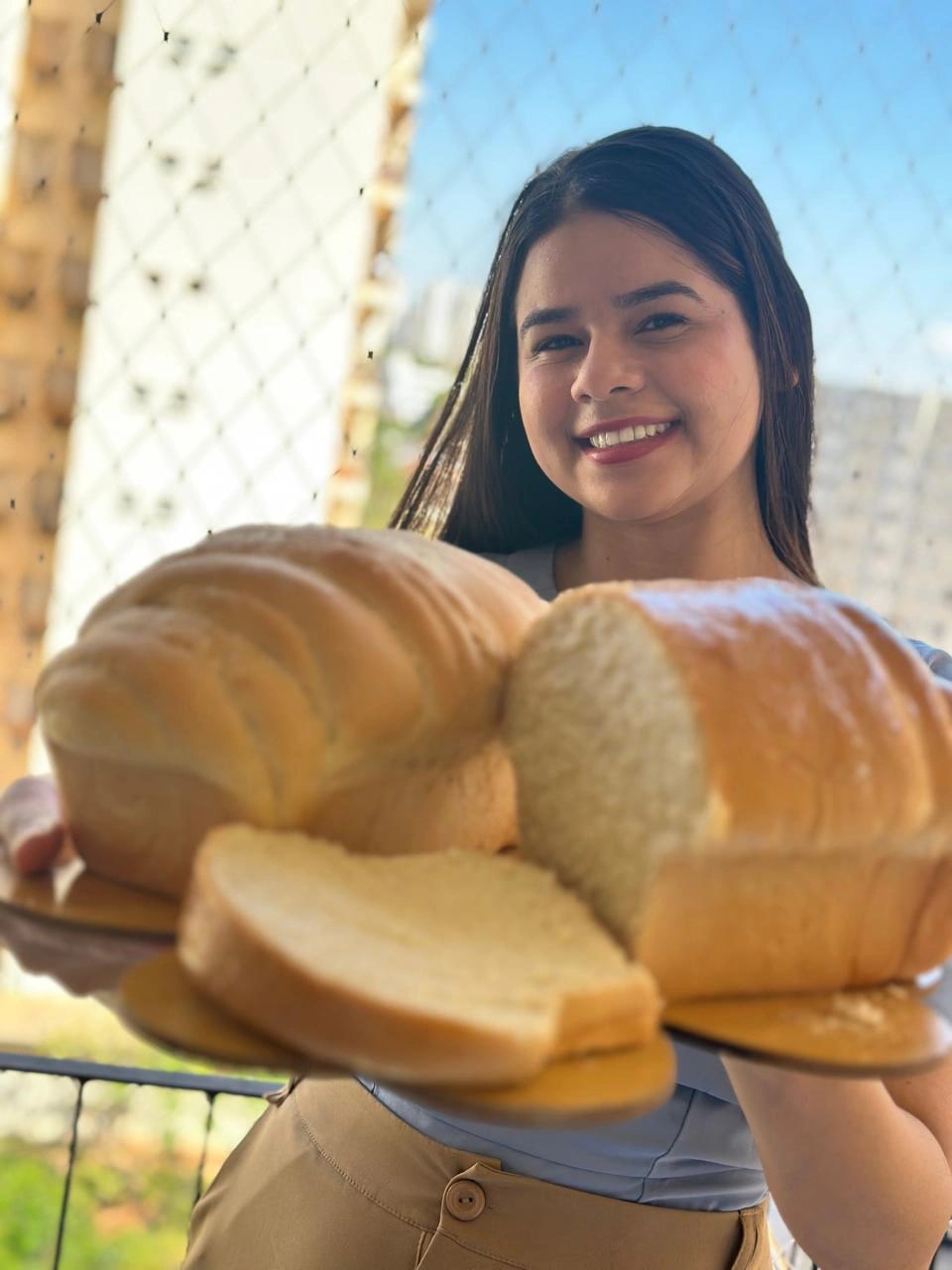 Mari sorrindo com dois pães caseiros e fatias na tábua